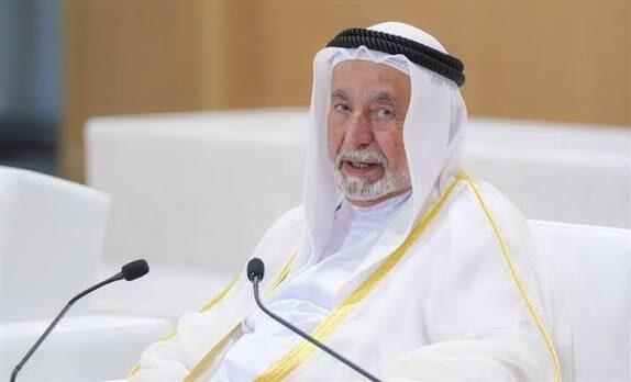Sultan Muhammad Al Qasimi seated at a conference table with a microphone during a formal session