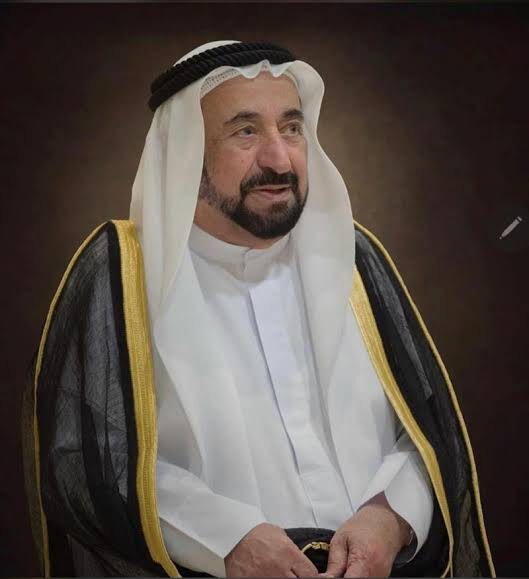 Formal seated portrait of Sultan Muhammad Al Qasimi against a dark background