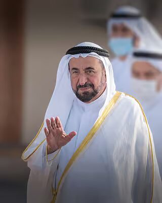 Sultan Muhammad Al Qasimi raising a hand in greeting on arrival at a public event