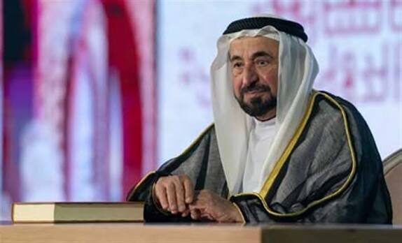 Sultan Muhammad Al Qasimi seated at a ceremonial table with an open volume before him